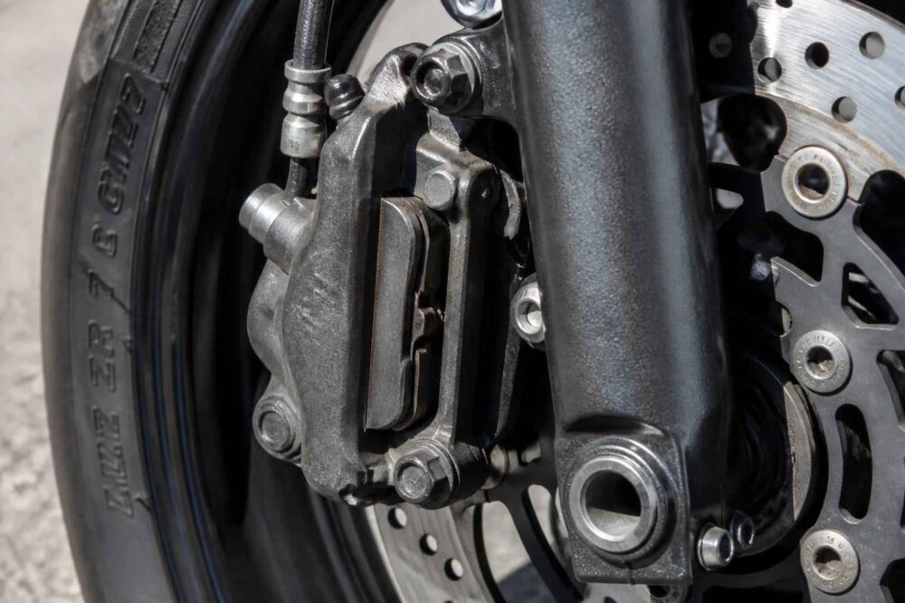 Przedni hamulec tarczowy motocykla Zbliżenie na klocki hamulcowe, zacisk i tarczę przedniego koła motocykla