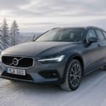 Szary Volvo V90 zaparkowany na ośnieżonej drodze w zimowym lesie sosnowym