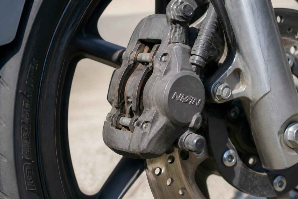 Zbliżenie na zacisk hamulca tarczowego i przednie koło motocykla